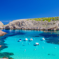 Cala Morell cove with its red rocks and crystal clear blue water, Menorca island, Balearic Islands, Spain.