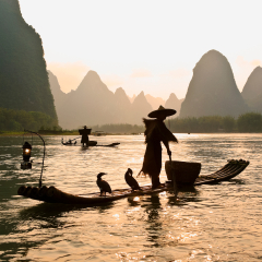 Silhouette of cormorant fishermen on the Li River (Lijiang) with karst peaks in the background at sunset, near Xingping, Guangxi Province, China