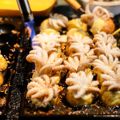 Fire cooking (Burning) for "Baby Octopus" in Takoyaki Japanese balls on black stove - Japanese food background or texture.