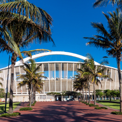 DURBAN, SOUTH AFRICA - FEBRUARY 23, 2018: Close up morning empty palm tree lined paved walkway leading towards Moses Mabhida stadium and clear blue sky in Durban, South Africa